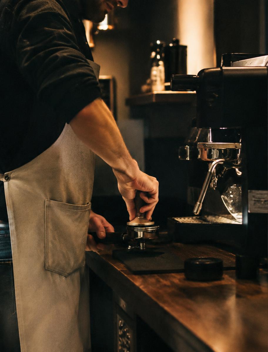 Barista tamping espresso behind the counter