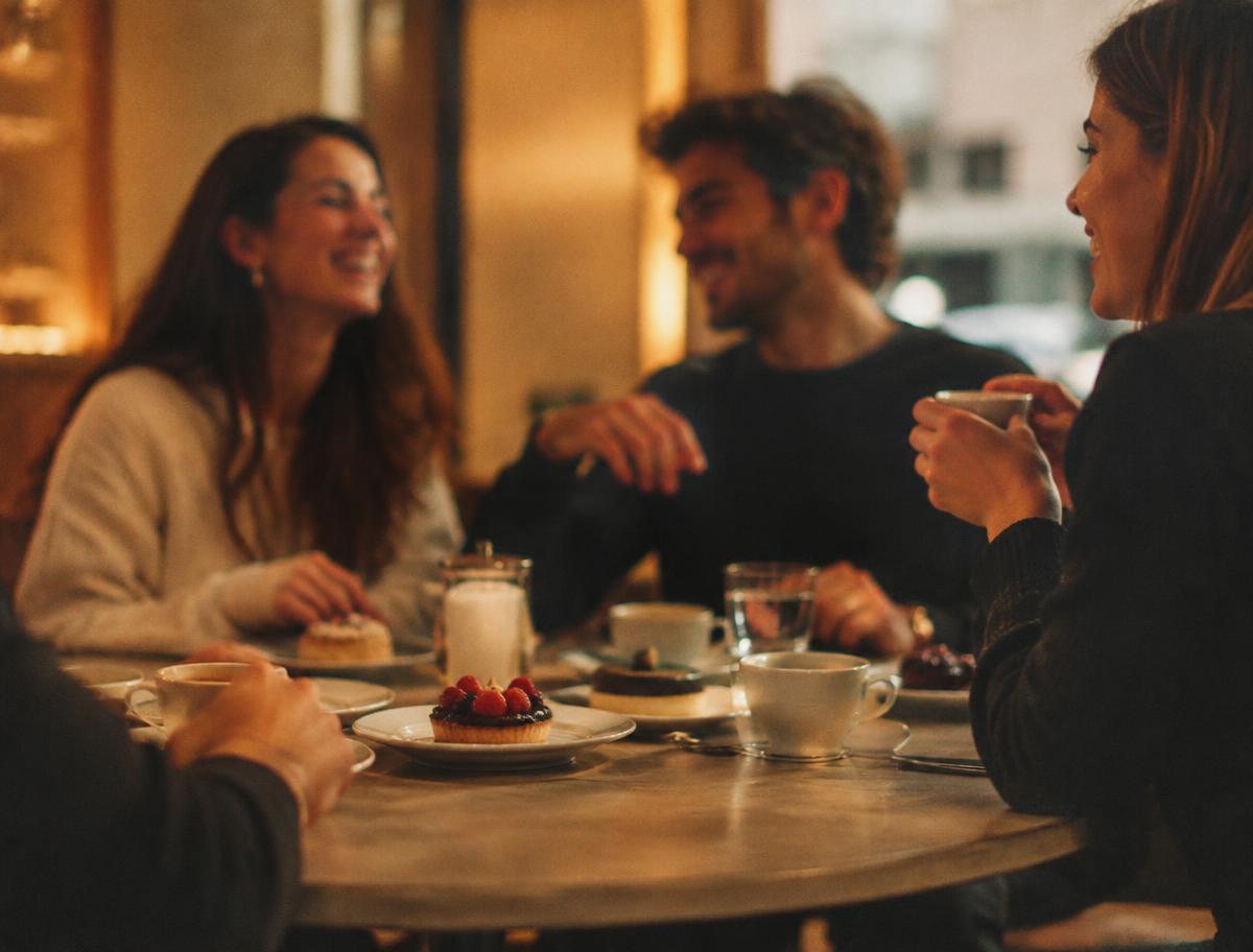 Friends sharing coffee and desserts at a café table